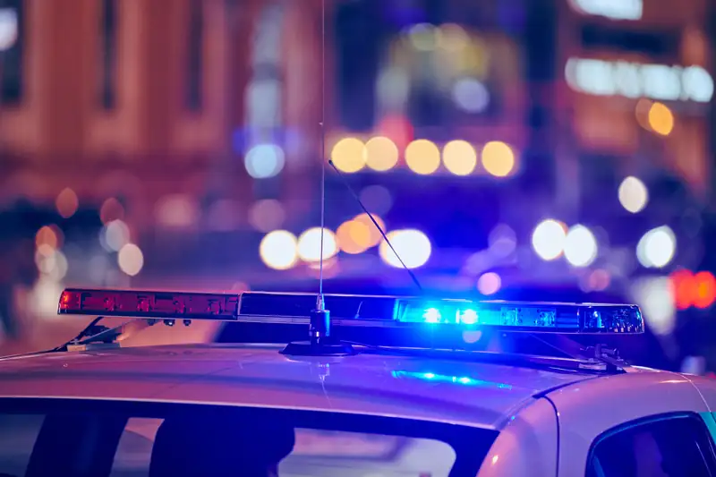 A patrol car’s light bar glowing blue on a city street at night